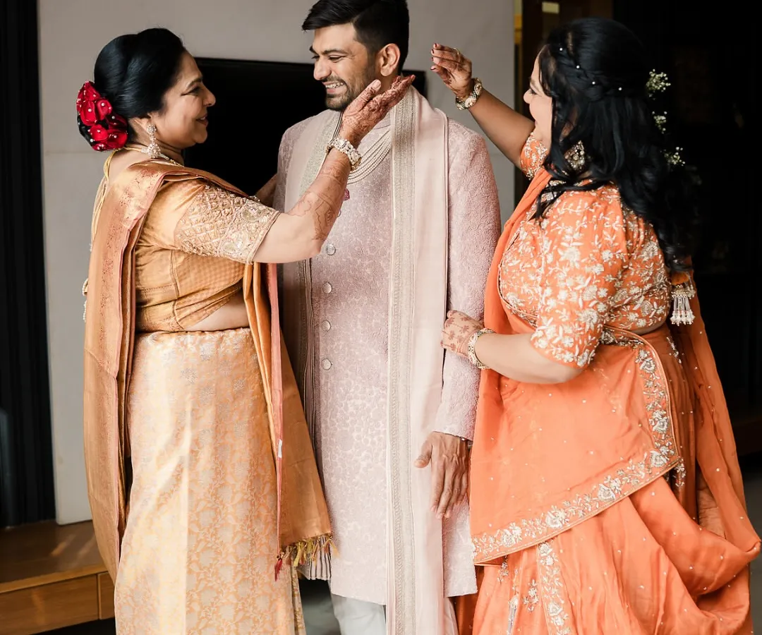 We believe in styling the entire family. Here, a groom shares a beautiful moment with his mother and aunt, both styled by us in elegant, coordinated attire that reflects their joy and importance on this special day.