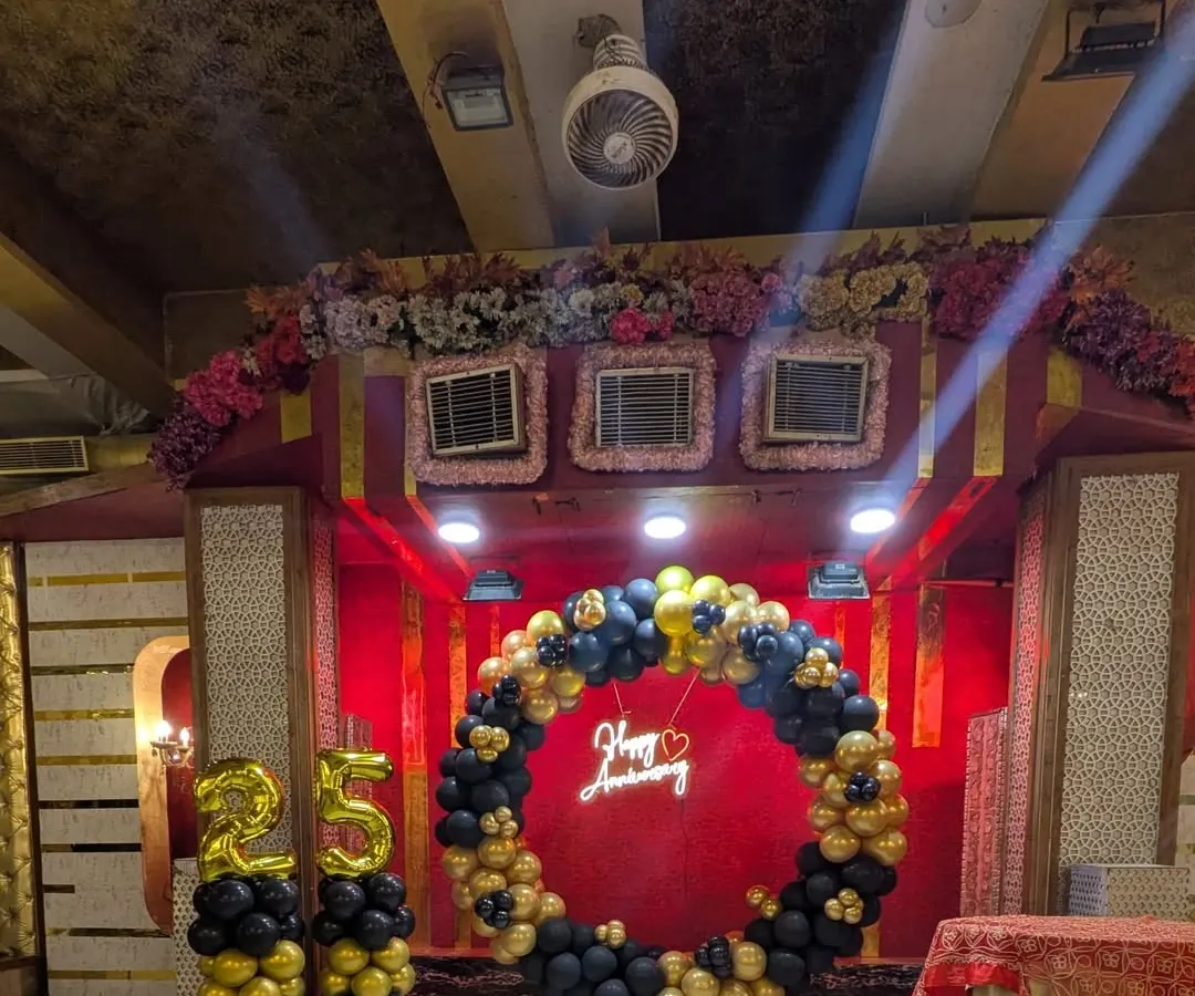 For a 25th anniversary, I created this elegant stage decoration. The setup includes a circular balloon arch in black and gold, a "Happy Anniversary" neon sign, and large foil number balloons, creating a perfect focal point for the celebration.