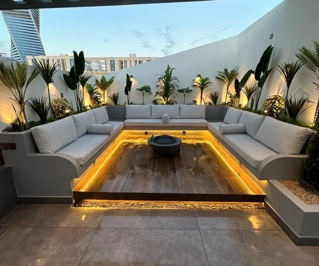We designed this modern rooftop lounge with a custom sunken seating area to create an intimate and luxurious space for entertaining. The design features integrated perimeter lighting under the U-shaped sofa and strategically placed uplighting on tropical plants to enhance the evening ambiance.