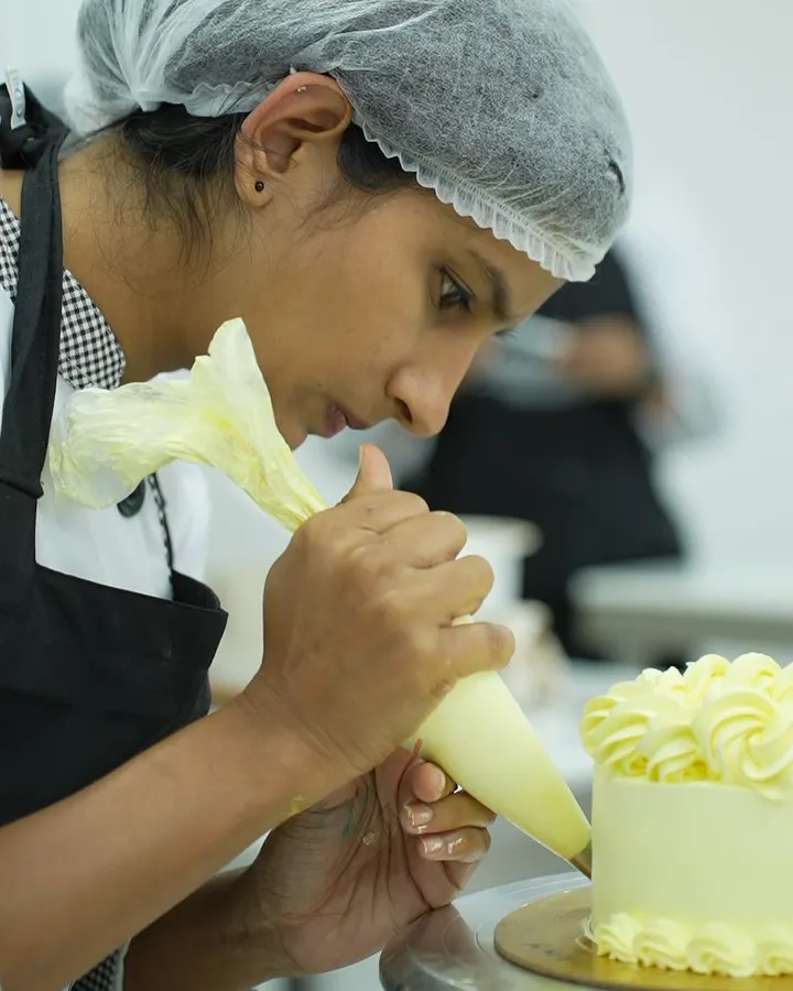 Here, I am guiding a student as she perfects her piping technique. In my class, you get complete hands-on practice, and I am right there to help you master the skills needed for professional cake and cupcake decoration.