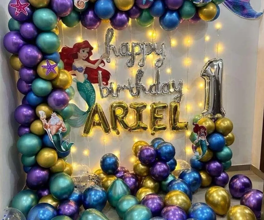 For a little girl's first birthday, I did this magical Little Mermaid theme. The balloon garland uses purple, teal, and gold balloons with seashell details. I also added Ariel character cutouts and fairy lights behind the 'Happy Birthday' foil balloons to make it sparkle.