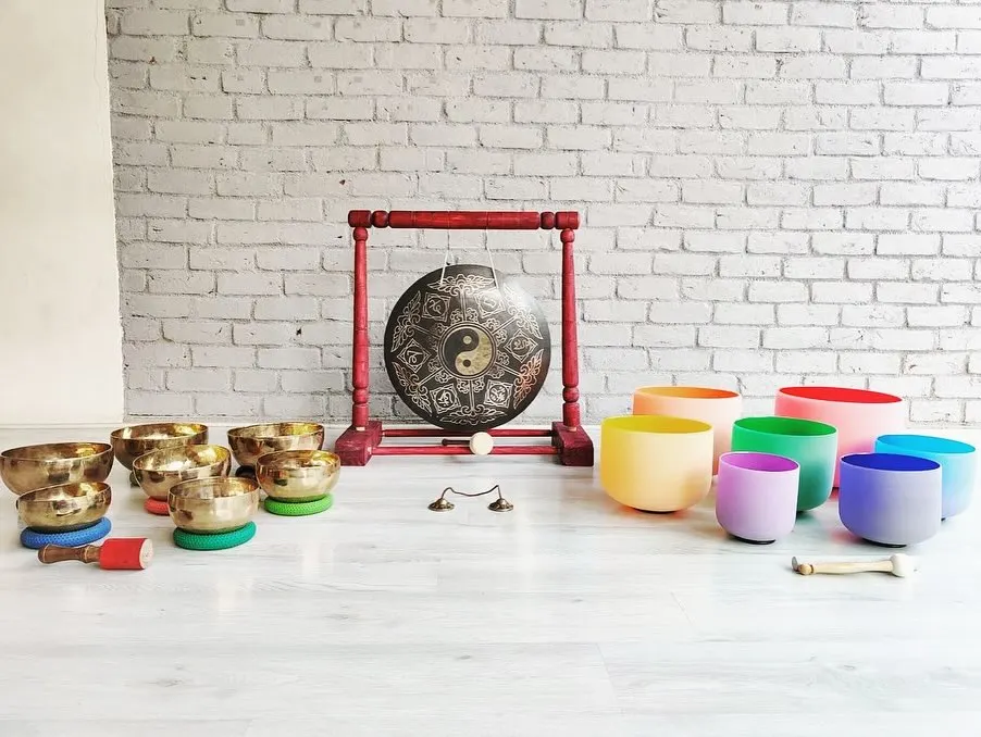 My shala is home to a wide array of sound healing instruments. This setup includes a collection of hand-hammered Tibetan bowls, colorful chakra-tuned crystal bowls, and a Yin-Yang gong, each with its own unique voice and healing properties.