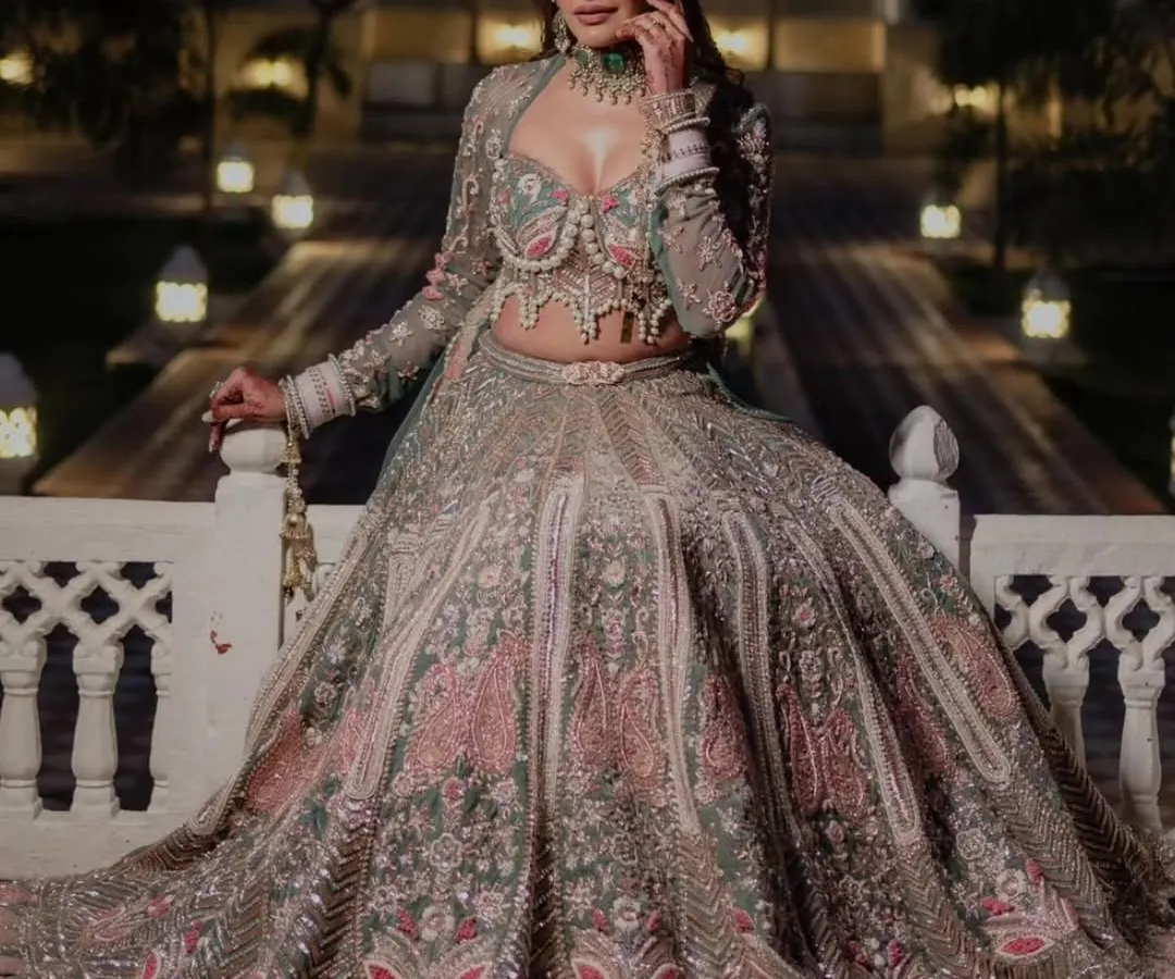 For the bride who wants to make a statement, we offer exclusive couture pieces for rent. This designer lehenga features a modern corset-style blouse with pearl detailing and a unique pastel floral skirt, perfect for a destination wedding or a grand reception.
