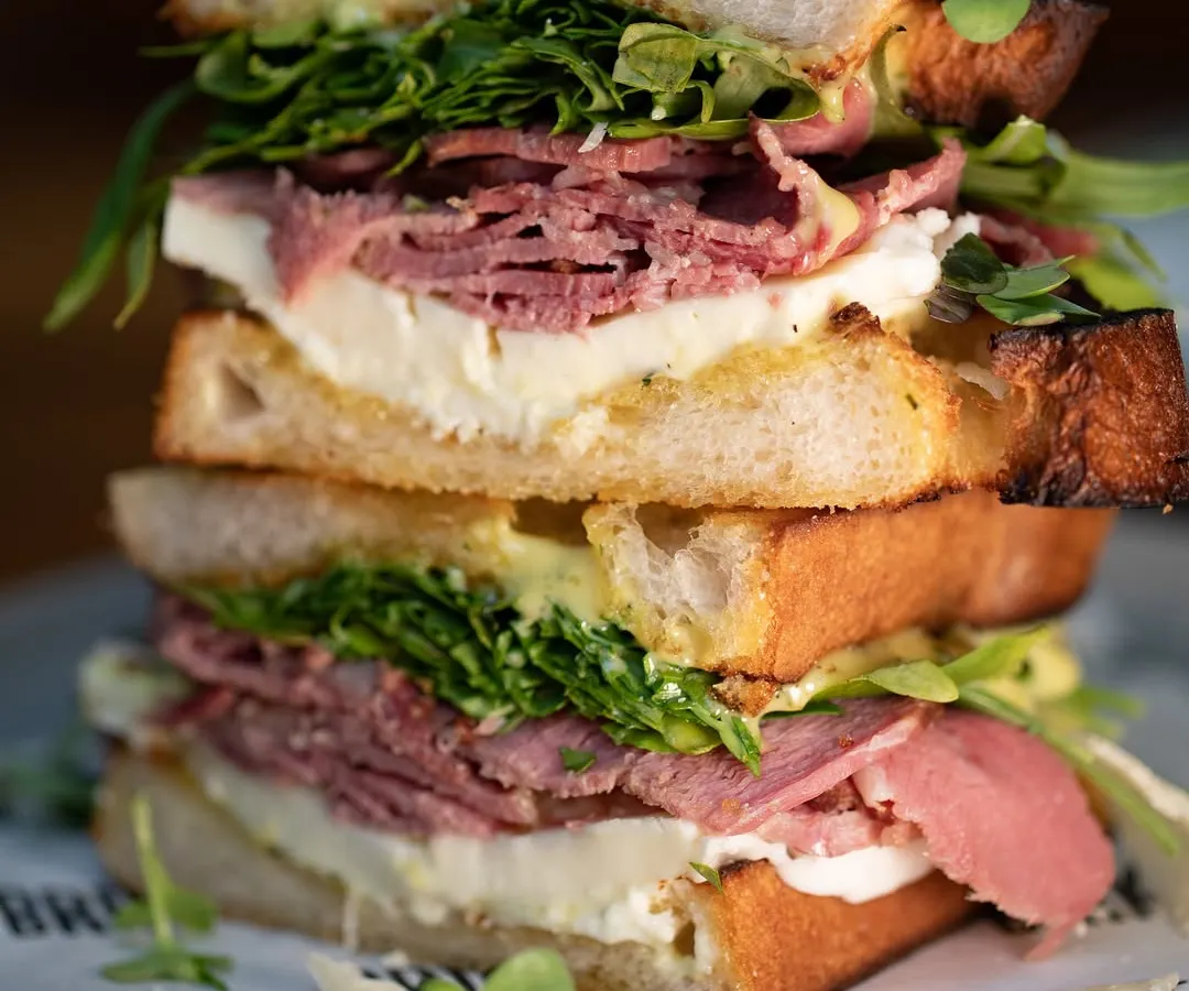 Meet our stacked pastrami sandwich. We pile tender pastrami, our fresh, handmade mozzarella, and crisp greens between slices of our naturally leavened sourdough. It’s a full meal and a testament to our love for big, bold flavors.
