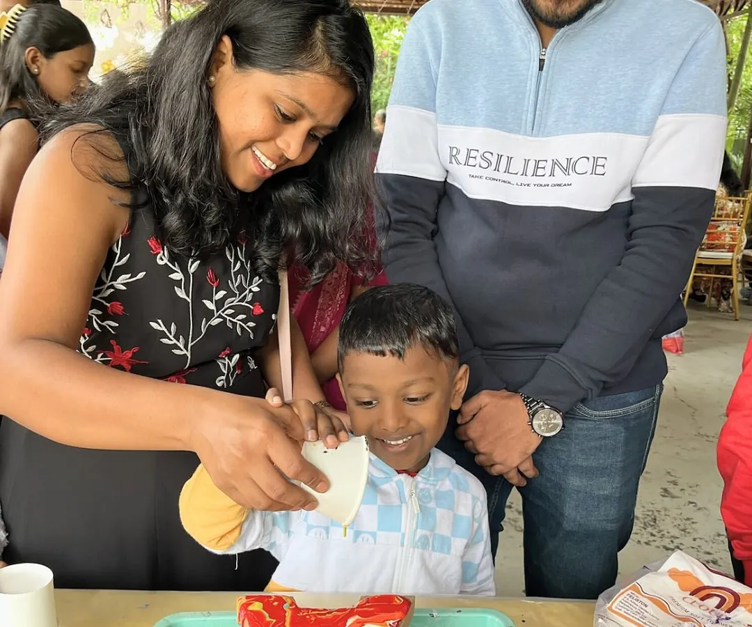 This is what pure family fun looks like. A mother and father help their son create his first fluid art masterpiece during a birthday party, full of smiles and colorful messes.