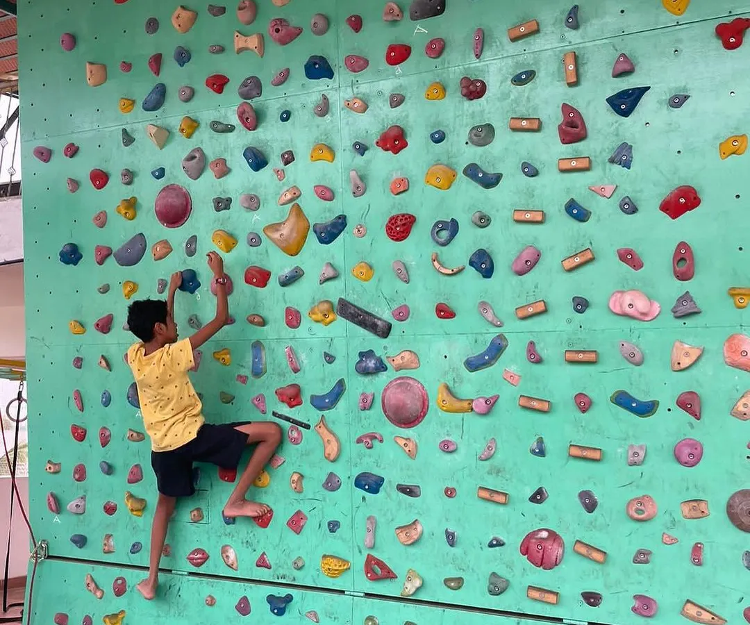 Here, a young climber navigates a bouldering route on our wall. We encourage kids to find their own path, focusing on the process of problem solving and building focus rather than just reaching the top.