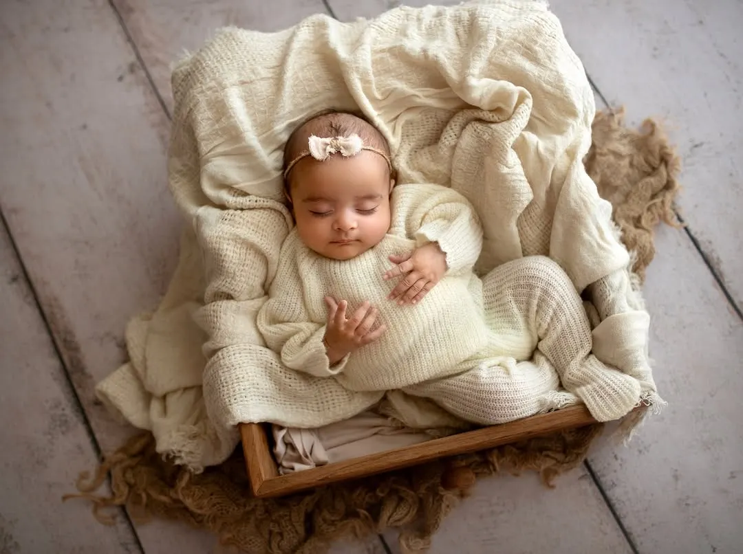 I believe in keeping things simple to let your baby's sweetness shine. This little one is sleeping peacefully in a cozy wooden box, nestled in soft, cream-colored knits, a perfect example of my safe and classic newborn photography style.