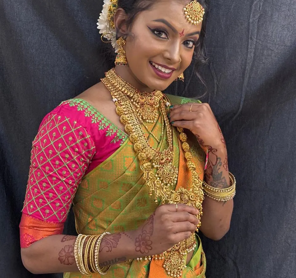 A joyful South Indian bride glowing on her special day. We focus on creating a look that feels authentic and beautiful, complete with traditional gold jewelry, intricate hairstyling with fresh flowers, and makeup that lasts through all the ceremonies.