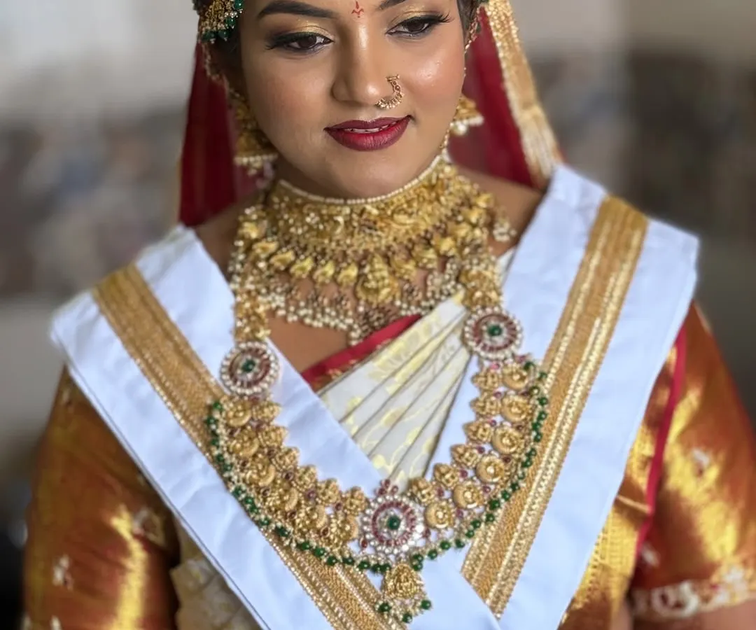 This is the traditional South Indian 'Goddess' look that I love creating for the Muhurtham. For Harshitha, we went with bold, 3D eyes and a classic red lip to complement her stunning gold jewelry and white Kanjivaram saree.