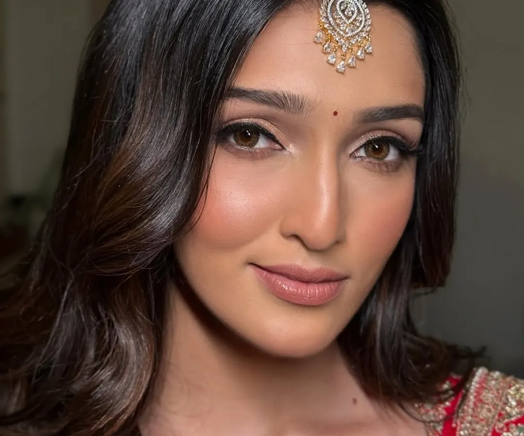 A close-up of a modern red bridal look. The focus here is on flawless skin and sharp, clean lines with a winged eyeliner and softly contoured features, proving that a traditional red lehenga can be both classic and contemporary.