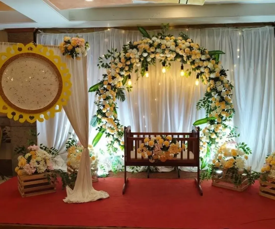 For this naming ceremony, I created a serene and beautiful space. The centerpiece is a traditional wooden cradle, framed by a lush floral arch of peach and white roses, with soft lighting to create a warm glow for the baby's big day.