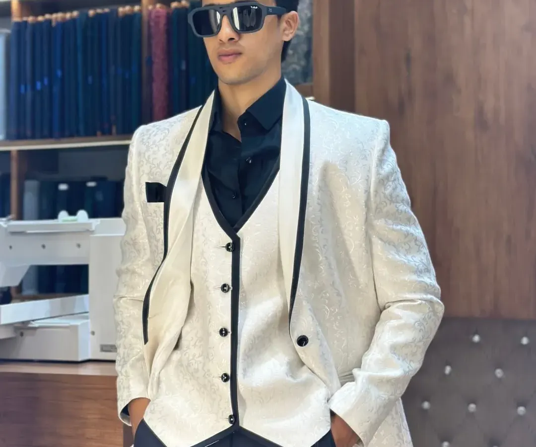 For the man who wants to own the room. A sharp white three-piece tuxedo with a contrasting black waistcoat and lapels, tailored for a flawless, modern silhouette.