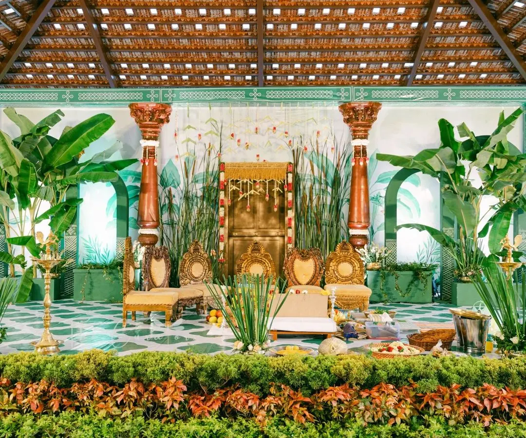 This Muhurtham setup reimagines tradition. We skipped a conventional mandap, using lush banana plants, antique temple pillars, and a stunning illustrated backdrop to create a stage that is both grand and deeply personal.