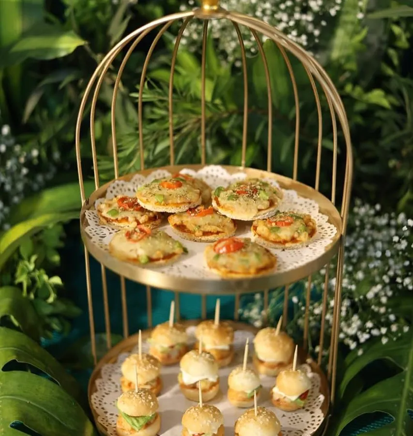 Our "mini food for the mini you" concept is a favorite. Here are our freshly made mini pizzas and burgers, served in a beautiful golden birdcage stand, perfect for a whimsical and delicious touch.