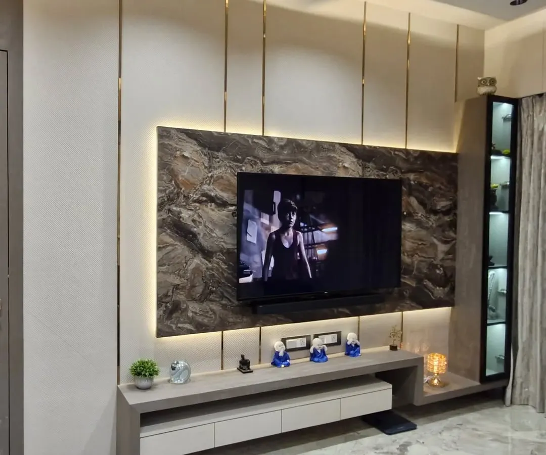 A TV unit can be the statement piece of your living room. For this space, I used a combination of a dark marble-finish panel, soft backlighting, and sleek metal inlays to create a modern and luxurious entertainment center.