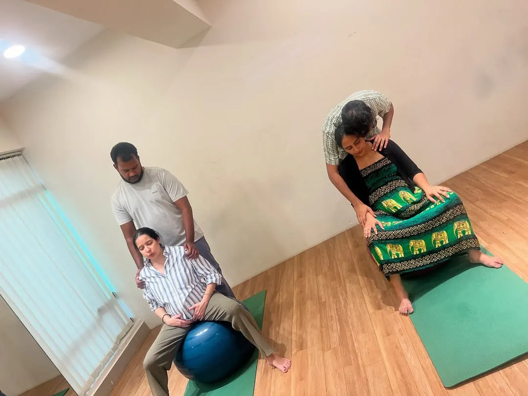 Here you can see couples in our Bangalore studio practicing partner-supported labor positions. We focus on hands-on techniques like using a birth ball for comfort and having your partner apply counter-pressure to ease back labor, ensuring you both feel prepared and connected.