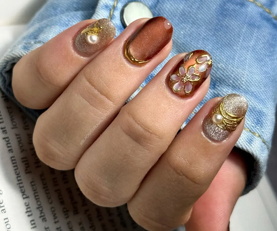 A perfect example of bridesmaid nails that are glamorous yet elegant. This set combines a glowing cat-eye base, hand-painted floral details, isolated chrome accents for sparkle, and delicate pearls. Every element is carefully placed to complement the wedding's festive atmosphere.