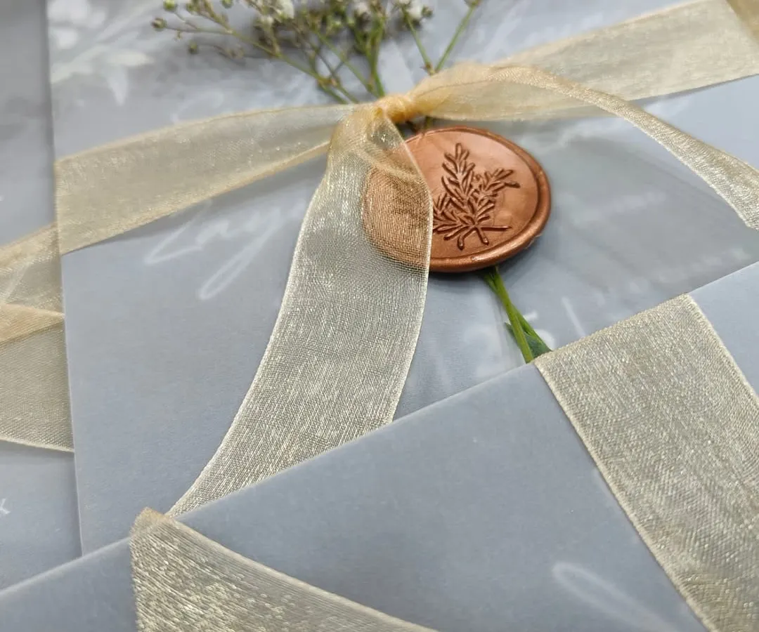 For a touch of timeless romance, I designed this invitation suite using a vellum wrap, secured with a delicate organza ribbon and a custom wax seal. The sprig of baby's breath adds a fresh, organic feel that's perfect for an elegant celebration.