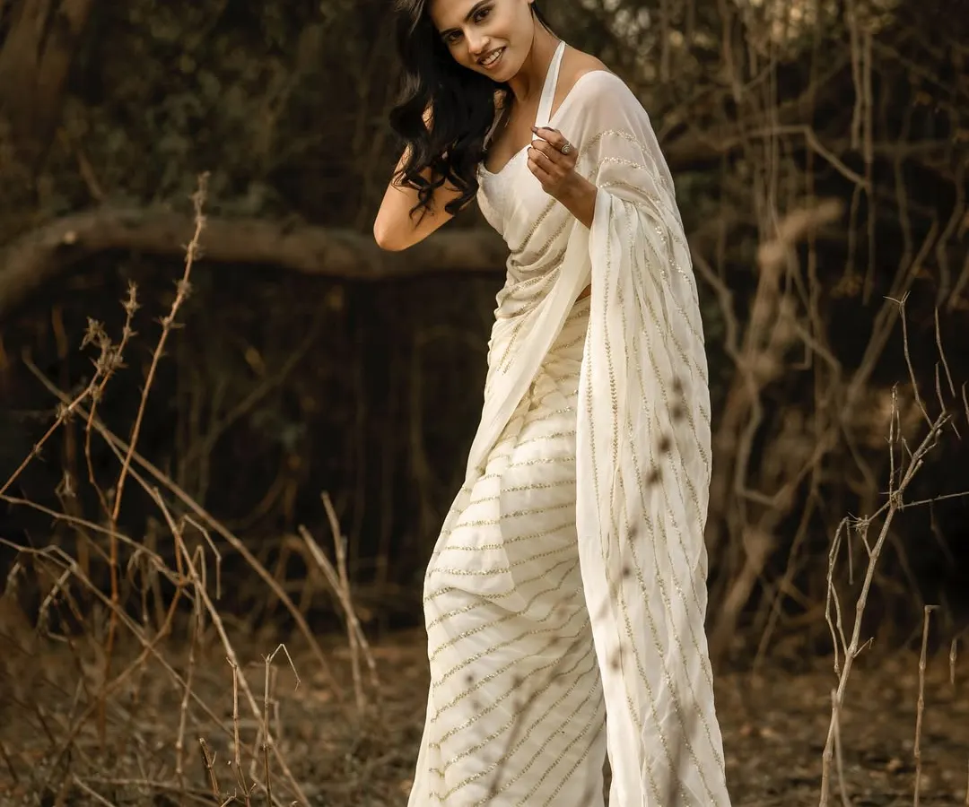 I love using the rustic landscapes around Mumbai to create soft, natural fashion portraits. This image, shot in a wooded area, uses the warm, diffused sunlight to create a gentle, ethereal mood that complements the flowing white saree. It’s a great example of a lifestyle fashion shoot.