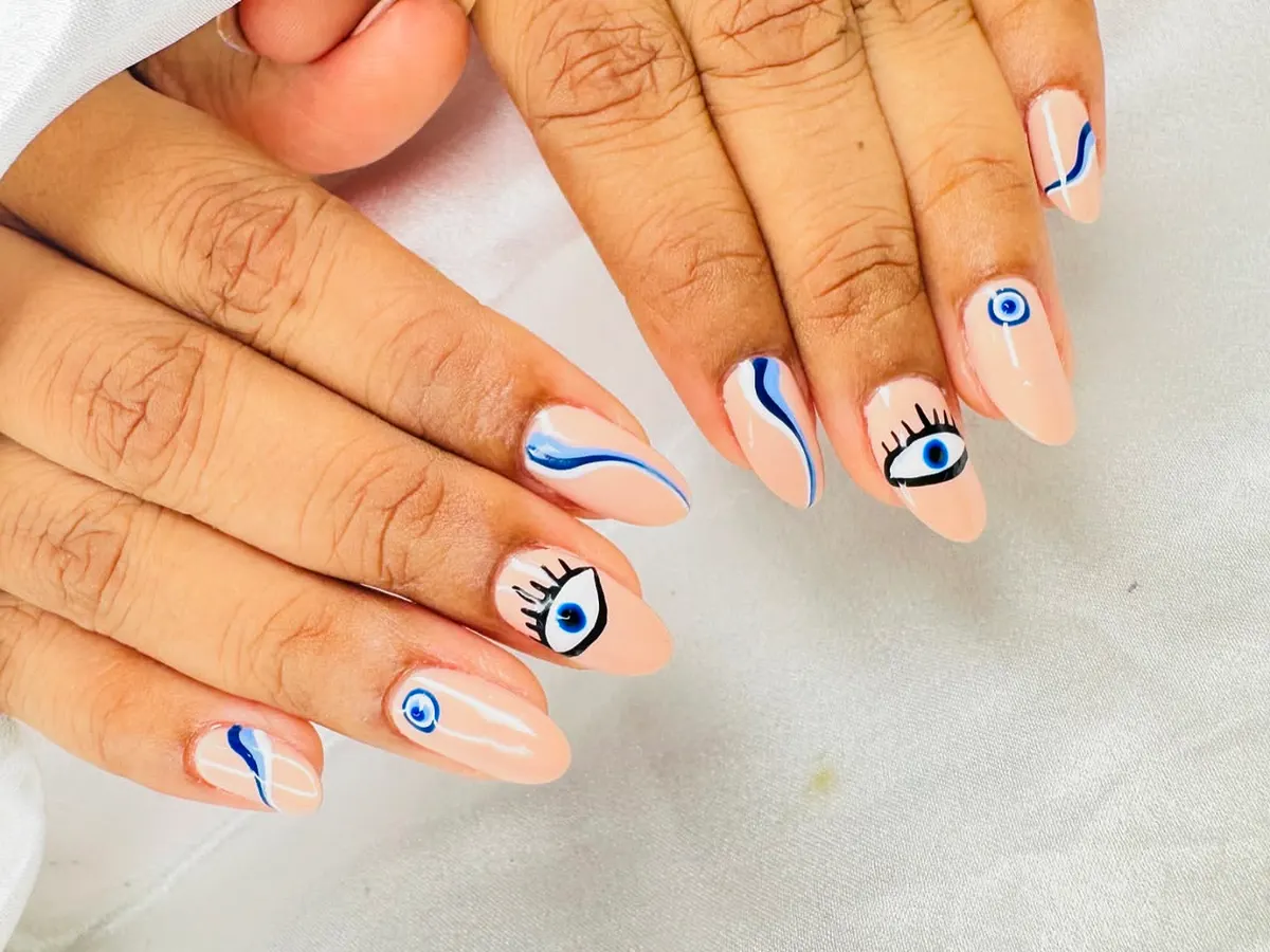 Keep the bad vibes away with this trendy evil eye nail art. I hand-paint each design on a clean nude base, combining detailed eye art with modern abstract blue swirls for a unique, protective style.