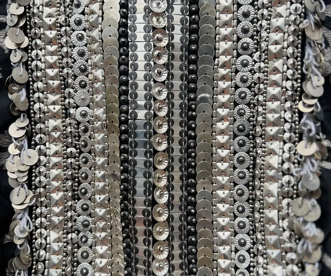 A detailed view of the meticulous hand embroidery on a brocade halter neck piece, showcasing rows of silver metal sequins and beads that create a stunning, light-catching texture.