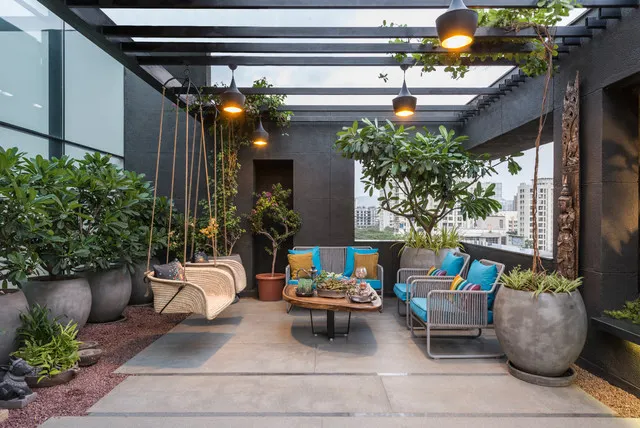 We created this elegant and comfortable terrace lounge, perfect for relaxing or entertaining. The design features a dark-toned pergola, a stylish swing, comfortable seating with vibrant cushions, and large planters with mature trees to create a private, green oasis.