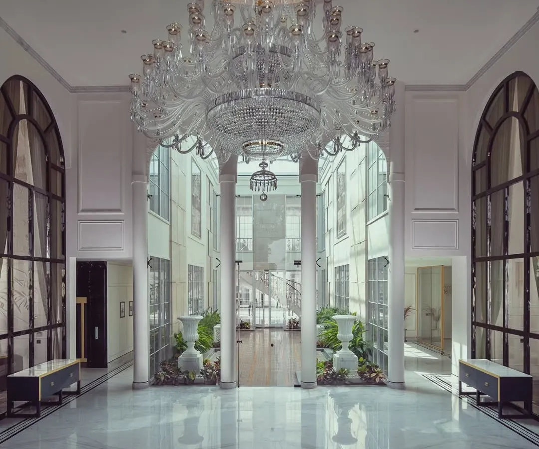 We believe a home's entrance should be a grand statement of what lies within. In this foyer for The Grand Alabaster, a magnificent crystal chandelier descends from a double-height ceiling, reflecting in the polished marble floors. This space was designed to create an unforgettable first impression of opulence and light.