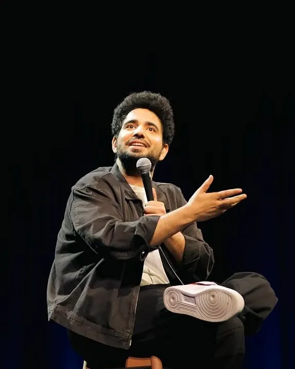 Comedian Samay Raina on stage during his standup special, with his custom "Unfiltered" Nike Air Force 1s prominently featured.