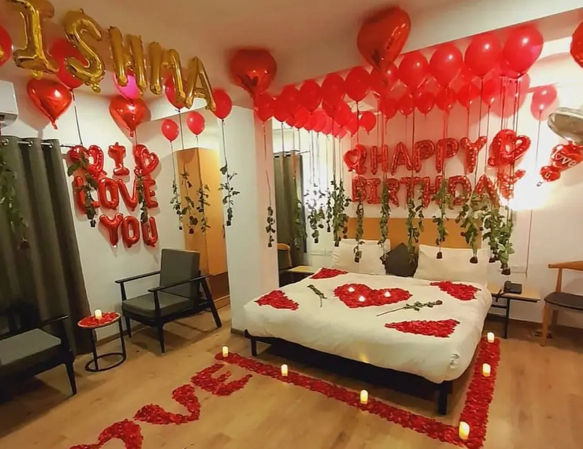 A complete room transformation for a birthday surprise, featuring a path of rose petals leading to the bed, "I Love You" messages, and a ceiling filled with red and heart-shaped balloons. This classic romantic decor is one of my most requested services.
