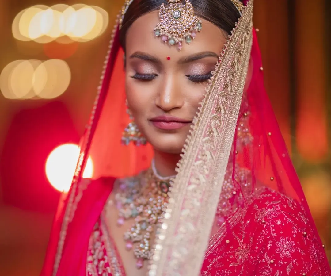 A bridal portrait is a moment of quiet reflection before a new beginning. I used the soft, ambient light to highlight her serene expression and the stunning details of her red bridal lehenga, creating a timeless, artistic photograph she will cherish forever.