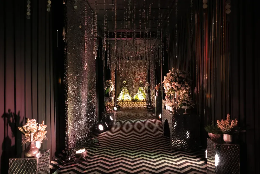 We believe the guest experience begins at the entrance. For this glamorous black and silver themed Sangeet, we designed a dramatic entryway with a chevron-patterned floor and shimmering crystal curtains, setting the stage for an unforgettable night of music and celebration.