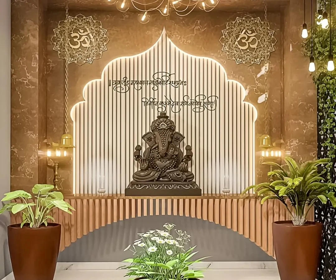 We designed this contemporary pooja space to be both serene and stylish. The design features a custom arch with LED backlighting against a fluted wood panel, a modern chandelier, and strategically placed plants to create a tranquil, nature-inspired ambiance for a Ganesha idol.