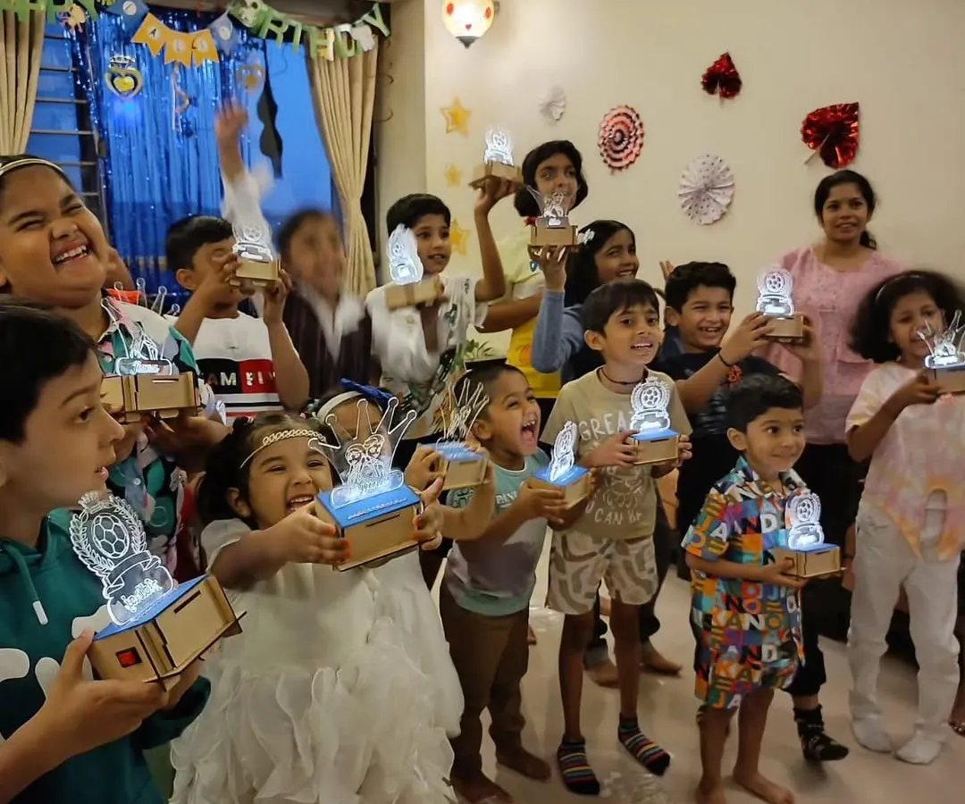 Look at these proud inventors! In our workshops, every child gets to build and take home their own creation, like these amazing custom light-up lamps. It's a glowing reminder of what they can achieve.
