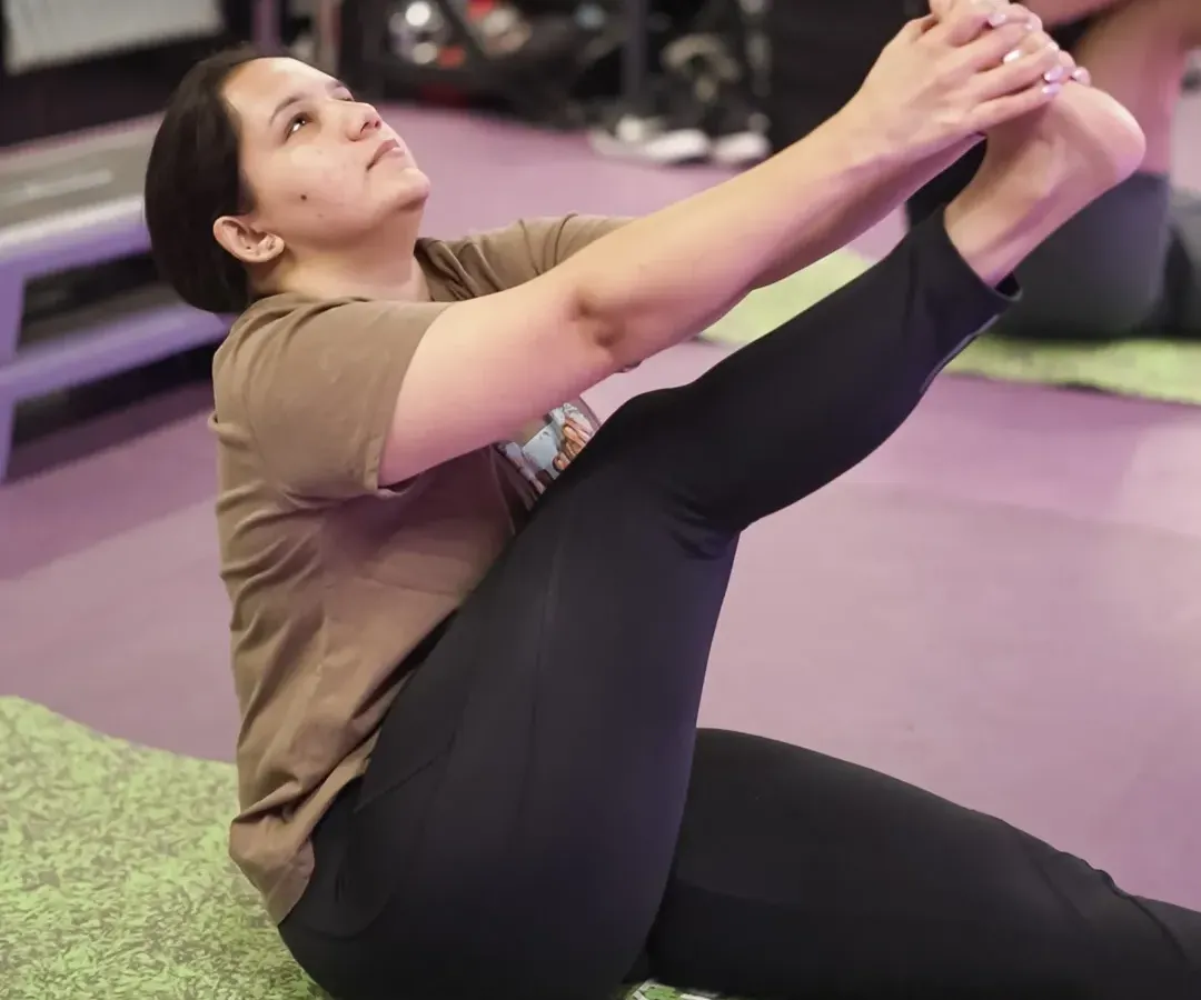 Find your focus and build strength in our group yoga sessions. This image captures a member deep in a stretch, showcasing the calm and determination that our yoga classes help cultivate on the mat.