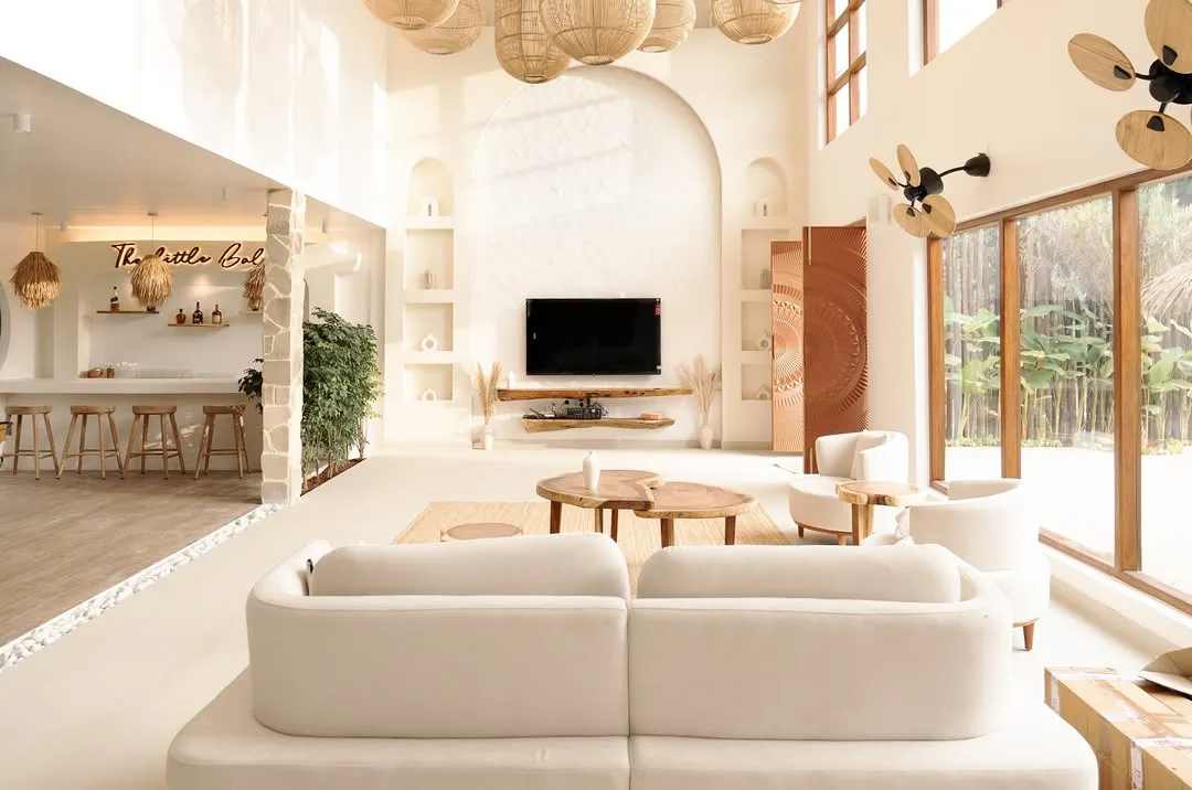 The heart of Artha Villa is this double-height living area, flooded with natural light. I used a palette of whites and earthy tones, with woven rattan lighting and natural wood furniture, to craft a space that feels both expansive and intimately comforting, embodying the spirit of a modern Balinese home.