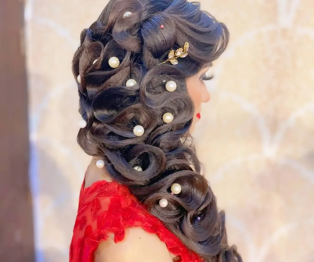 A perfect example of a glamorous reception hairstyle you will master. This look involves creating soft, cascading curls and expertly placing pearl accessories for a timeless and elegant finish.