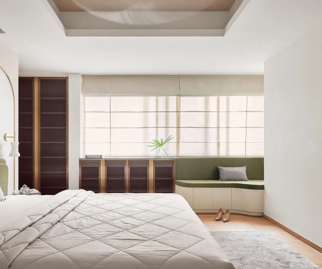 In this master bedroom, I integrated form and function with custom floor-to-ceiling wardrobes in a bold, dark finish with brass accents. The design is complemented by a custom window seat with built-in storage, creating a cozy reading nook that is both beautiful and practical.
