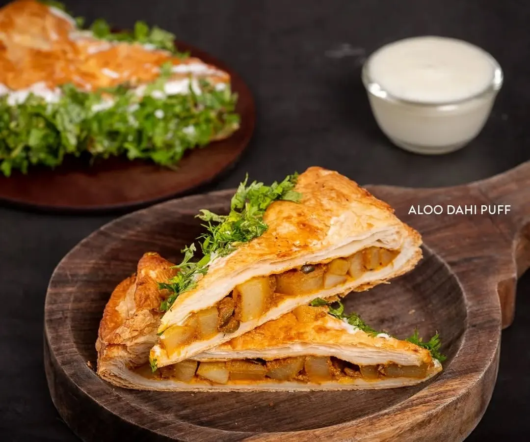 Meet the legend: our Aloo Dahi Puff. It's a unique creation with a flaky, golden crust filled with a tangy potato and yogurt mix, then topped with fresh coriander. It’s the perfect savory snack.
