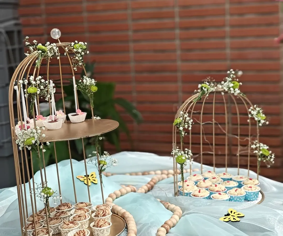 We bring the sweetness to your celebration with our elegant dessert table setups. This display, featuring a variety of our cupcakes and treats in decorative birdcages, was designed for a beautiful outdoor party.