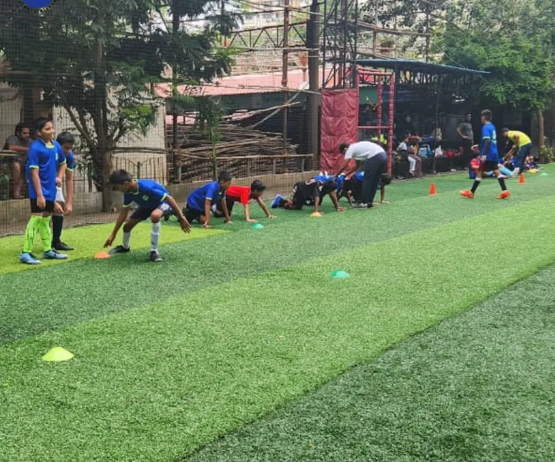 Excellence begins with the fundamentals. Here, one of our expert coaches provides hands-on instruction during a football training drill, focusing on skill development and tactical awareness on an artificial turf pitch.