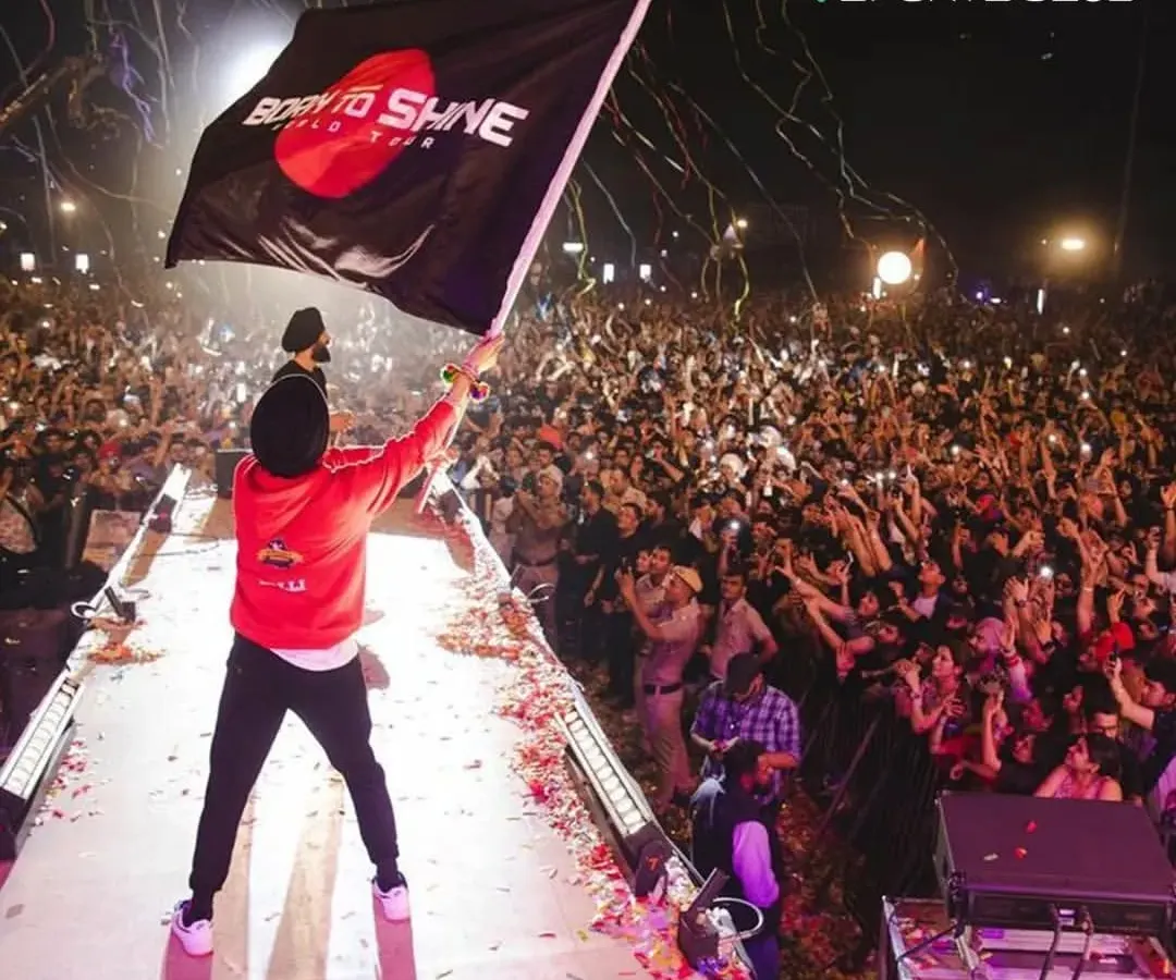 The energy is electric when a star like Diljit Dosanjh takes the stage, waving a 'Born to Shine' tour flag over a sea of thousands of cheering fans and phone lights.