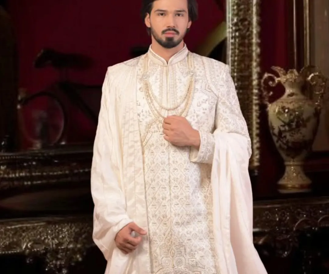 This is our classic ivory white sherwani, a timeless choice for any groom. We focus on intricate embroidery and a majestic fit, ensuring you look nothing less than royalty on your wedding day. We can customize the fabric and detailing just for you.