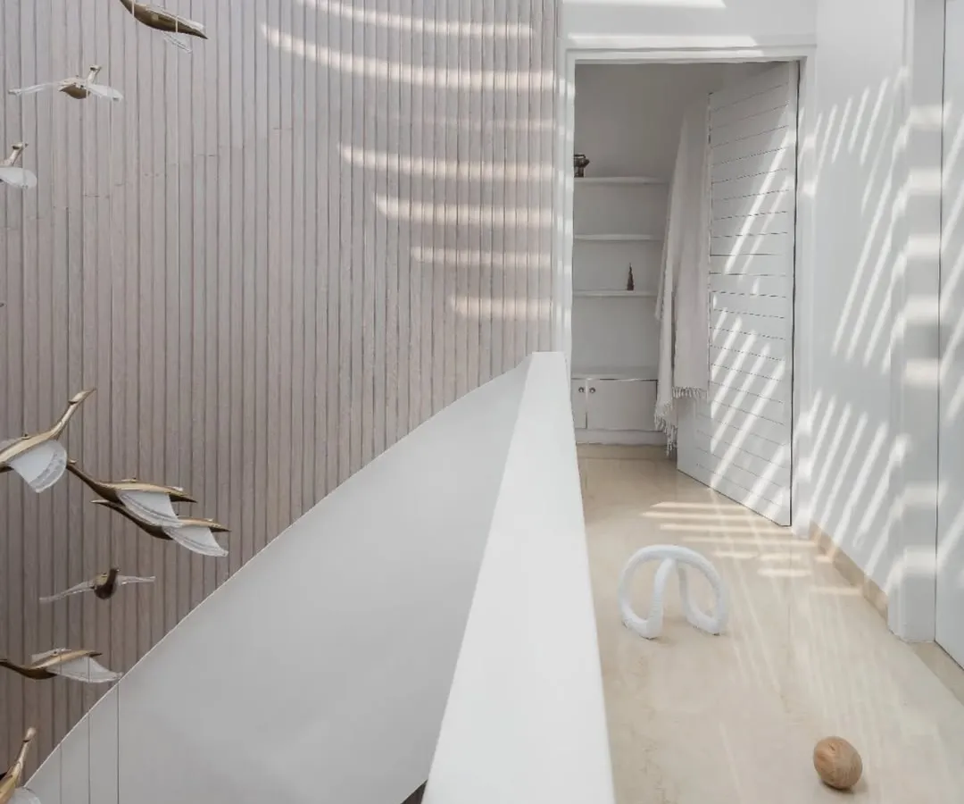 In this penthouse, I designed a helical staircase to be more than just a way to move between floors; it's a fluid, sculptural element. Bathed in light from a large skylight, its form contrasts with the clean, linear fluted wood wall, creating a focal point that is both art and architecture.