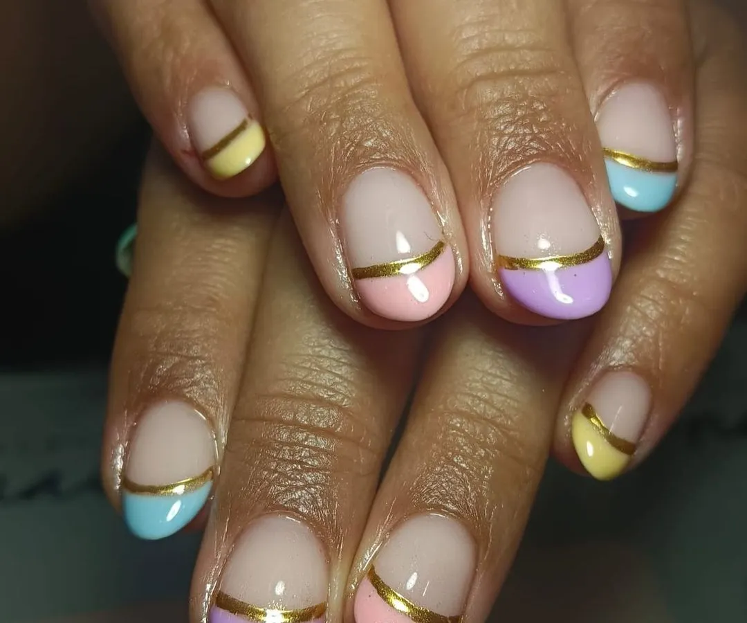 I am obsessed with this creative take on the French manicure. This look features soft pastel tips in pink, lilac, yellow, and blue on natural nails, accented with a clean gold stripe for a chic finish. A strengthening gel overlay ensures the design lasts and helps your nails grow strong.
