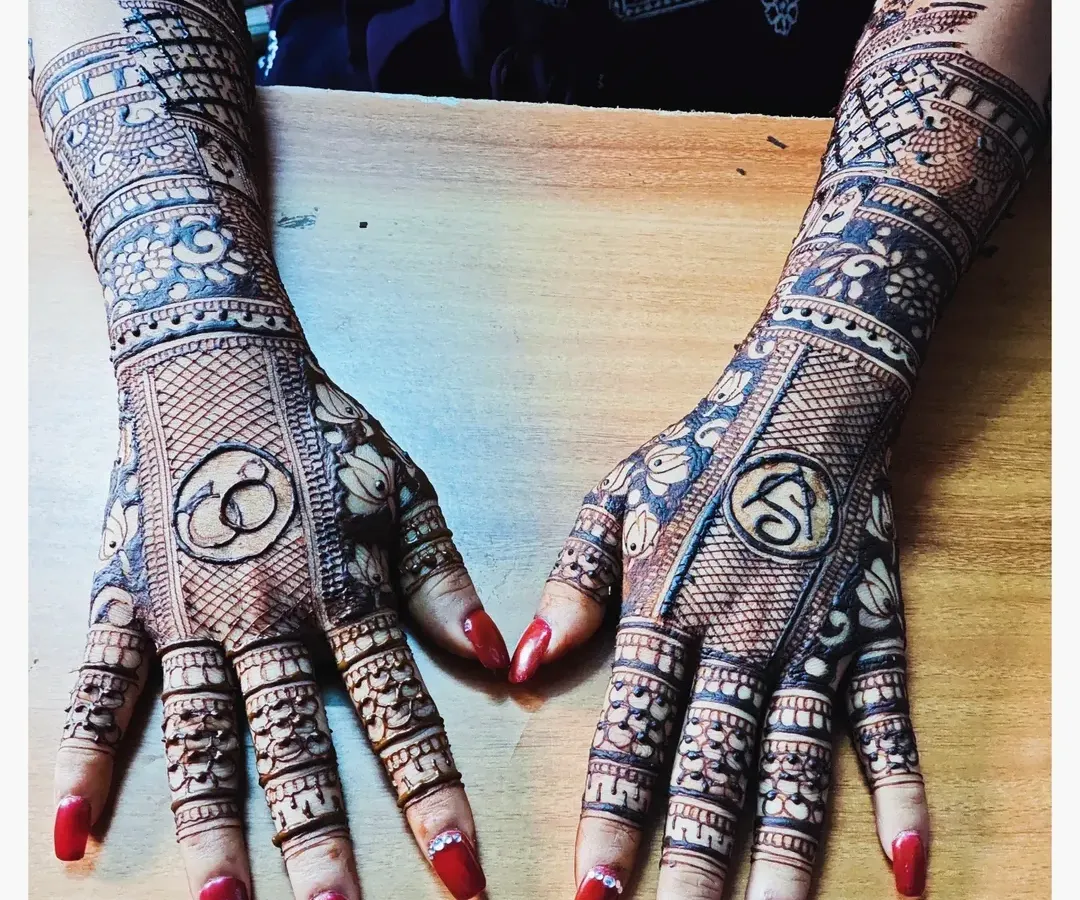 For engagement ceremonies, I can weave your story into the henna. This design features the couple's initial 'S' and a symbol of their union with interlocking rings, making it a truly personal piece of art.