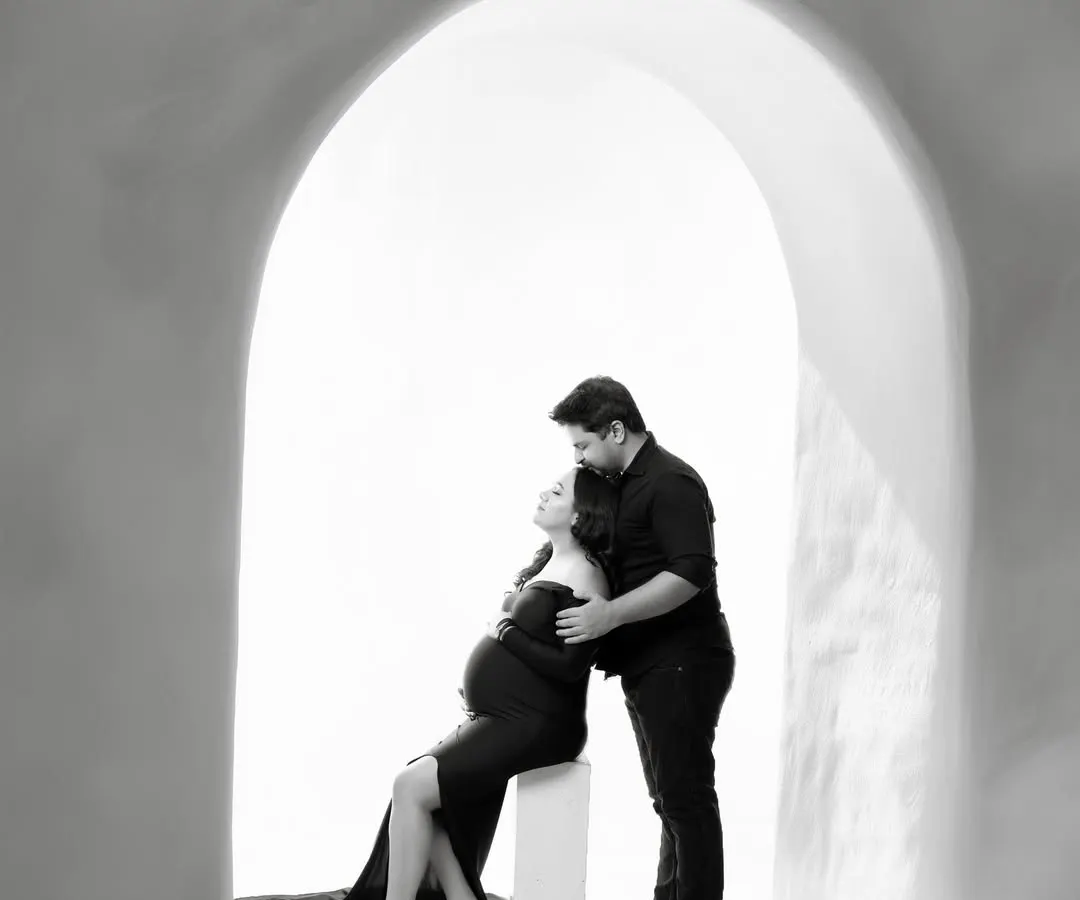 Sometimes, the most powerful stories are told in black and white. This intimate couple portrait, framed by a simple archway, focuses purely on the connection and anticipation between two people about to become parents.