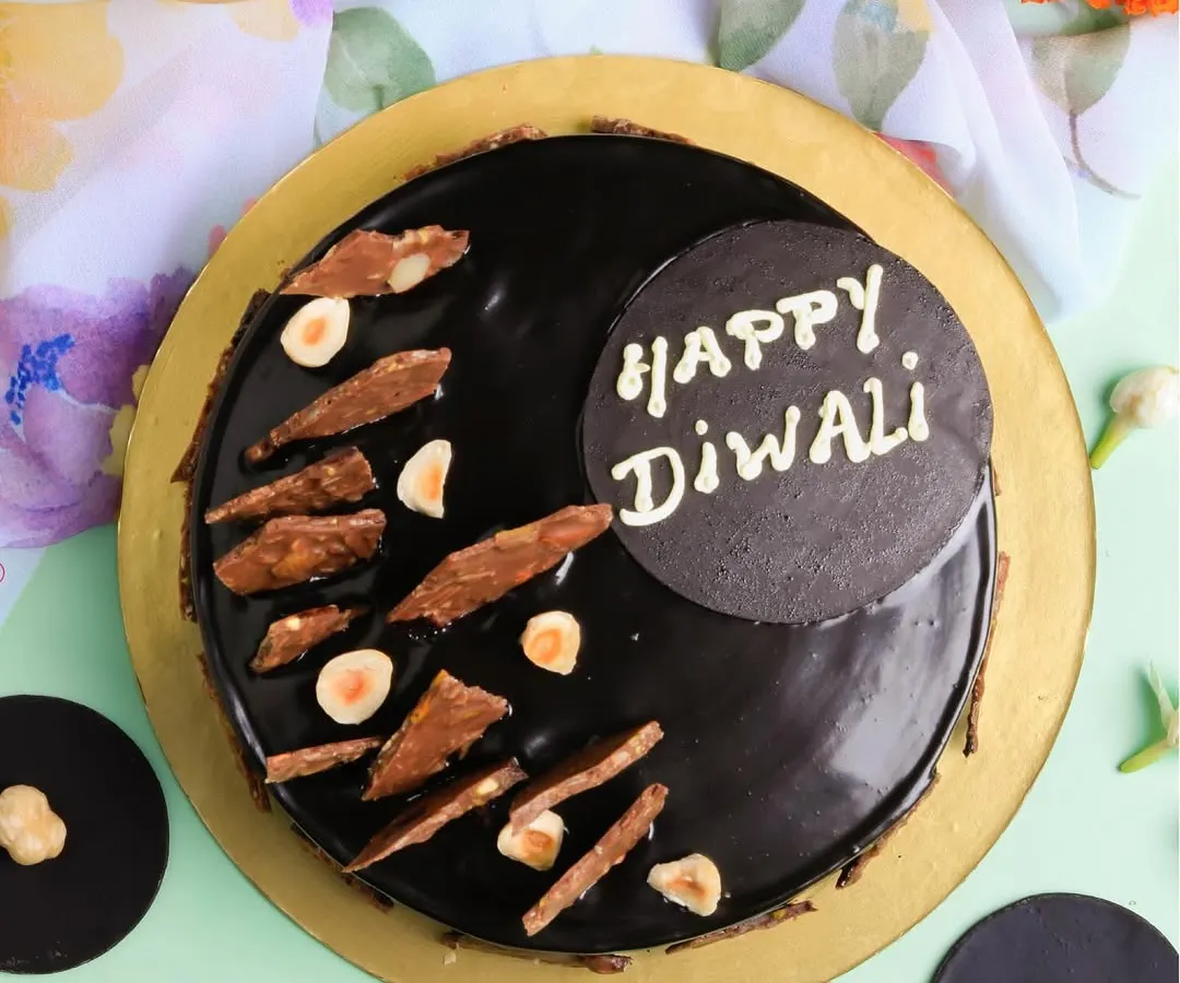 Celebrate Diwali with our indulgent Hazelnut Truffle Cake. This rich, glossy chocolate cake is topped with crunchy hazelnuts and a festive "Happy Diwali" message, offering a modern and luxurious centerpiece for your celebrations.