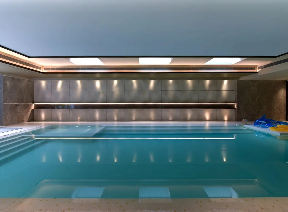This sleek indoor swimming pool is a private sanctuary for year-round wellness. We designed the space with clean lines, sophisticated wall textures, and integrated ceiling lights that reflect beautifully on the water's surface, creating a calm and luxurious atmosphere.