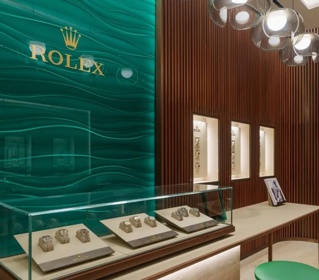 For the Rolex flagship boutique in Mumbai, we translated the brand's 119-year legacy into a physical space. The design uses a restrained palette of warm wood, travertino cladding, and the signature Rolex green to create an atmosphere of timeless elegance and refinement.