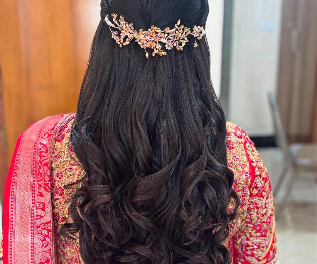 This is a popular half-up, half-down hairstyle, perfect for a sangeet or reception. It features voluminous, bouncy curls and is finished with a delicate, sparkling hair accessory for a touch of modern elegance.